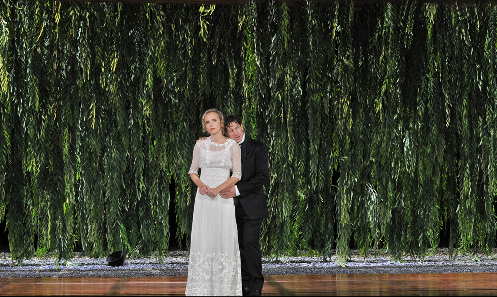 Ehepaar Hofreiter (Juliane Köhler und Tobias Moretti) vor Grünvorhang und im Angesicht einer kalten Ehebeziehung: "Das weite Land" am Münchner Residenztheater.