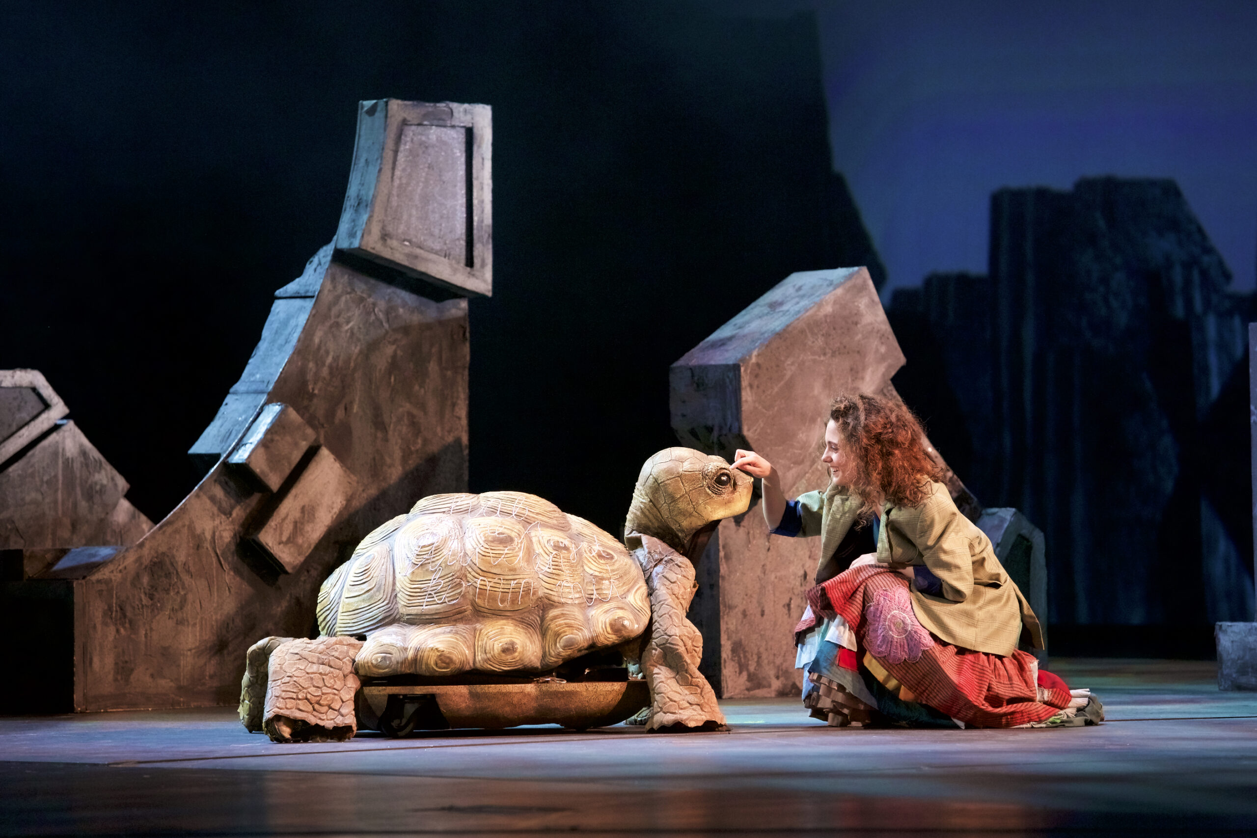 Momo (Anna Woll) streichelt die Schildkröte Kassiopeia (Ina Bures).