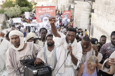 Jesus (Yvan Sagnet) mit seinen Jüngern in der Stadt in Milo Raus Film