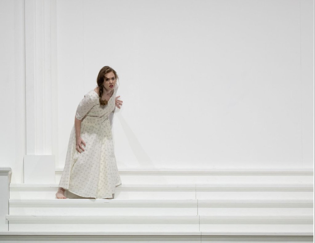 Eine Frau in einem langen weißen Kleid steht auf dem oberen Ende einer weißen Adresse.