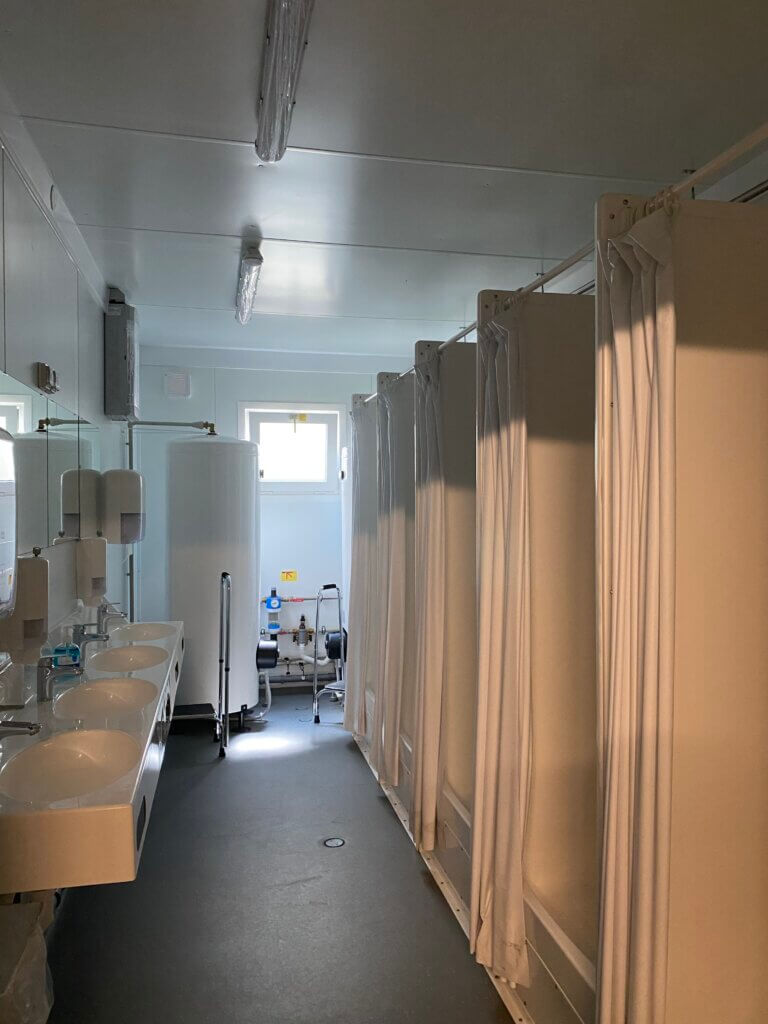 Blick in einen Raum, rechts sind Duschkabinen, links Wachbecken