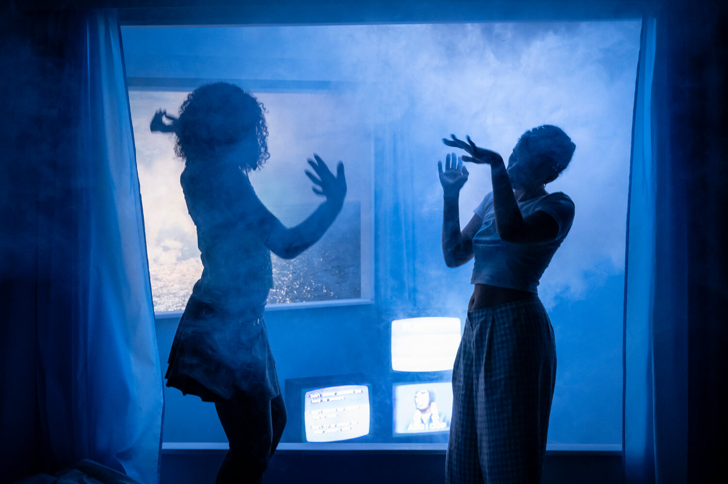 Cleo und Kara sind nur als Schatten zu sehen. Sie tanzen durch ein nebeldurchflutetes Zimmer.