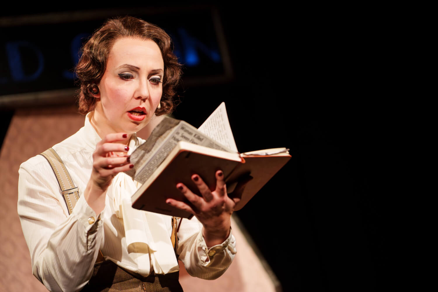 Marion Wulf (Agatha Christie) blättert konzentriert durch ein Buch, dass sie aufgeschlagen in den Händen hält.