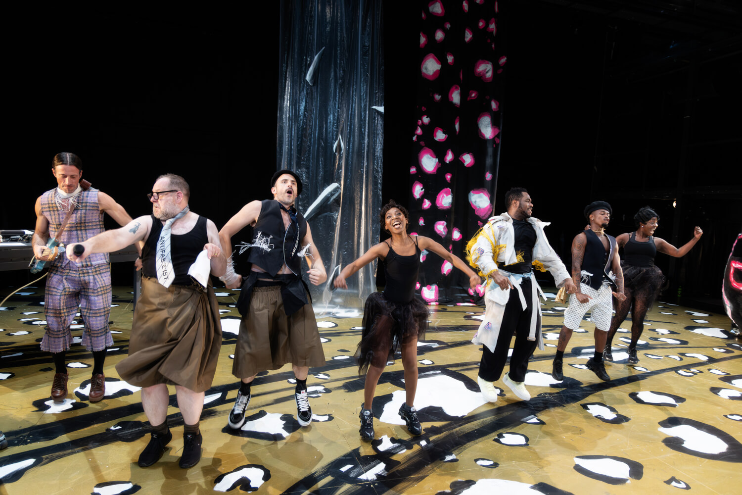 Das Ensemble tanz in einer V-Konstellation. In der Mitte tanzt eine wie Josephine Baker angezogene Person.