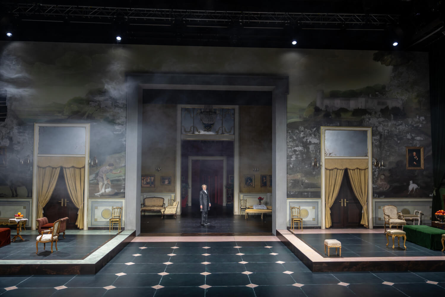 Aufführungsfoto von „Il Gattopardo“ von Giuseppe Tomasi di Lampedusa am Schauspielhaus Zürich. Ein großer, dreidimensional gestaffelter Bühnenraum mit Marmorboden und Einrichtungsgegenständen. Ein Mann steht verloren in der Mitte des Raumes.