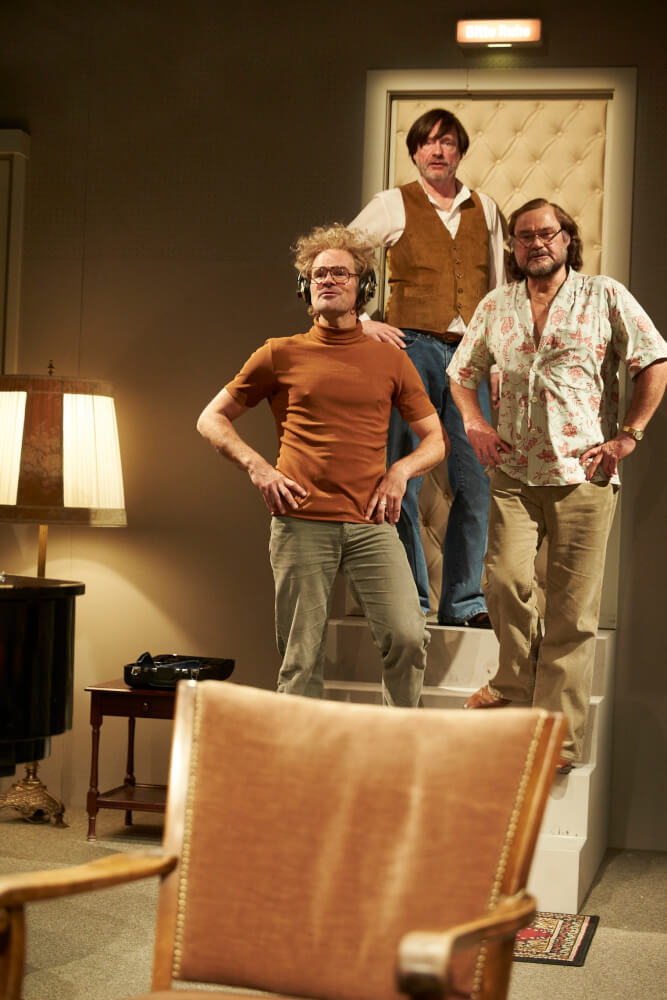 Aufführungsfoto von „Effi Briest“ von Bürk und Sienknecht. Drei Männer stehen versetzt auf einer schmalen Treppe mit vier Stufen. Die Hände in die Hüften gestemmt.