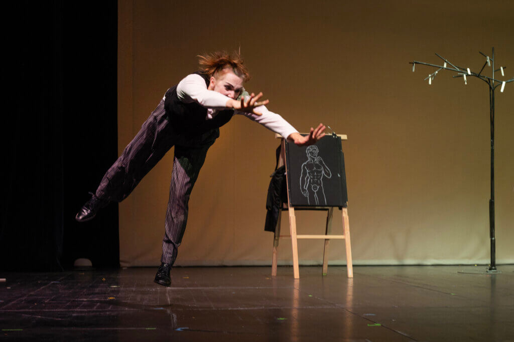 Aufführungsfoto von „Game of Clowns“ von Erkan Uyaniksoy der Bremer Shakespeare Company. Eine Frau springt mit allen vier Gliedern von sich gestreckt.