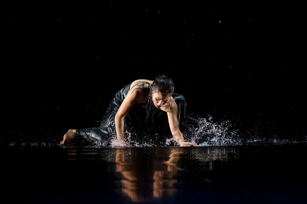 Noriko Nishidate kniet auf dem Boden. Ihre Hände wirbeln das seichte Wasser auf, das in den Boden eingelassen ist.
