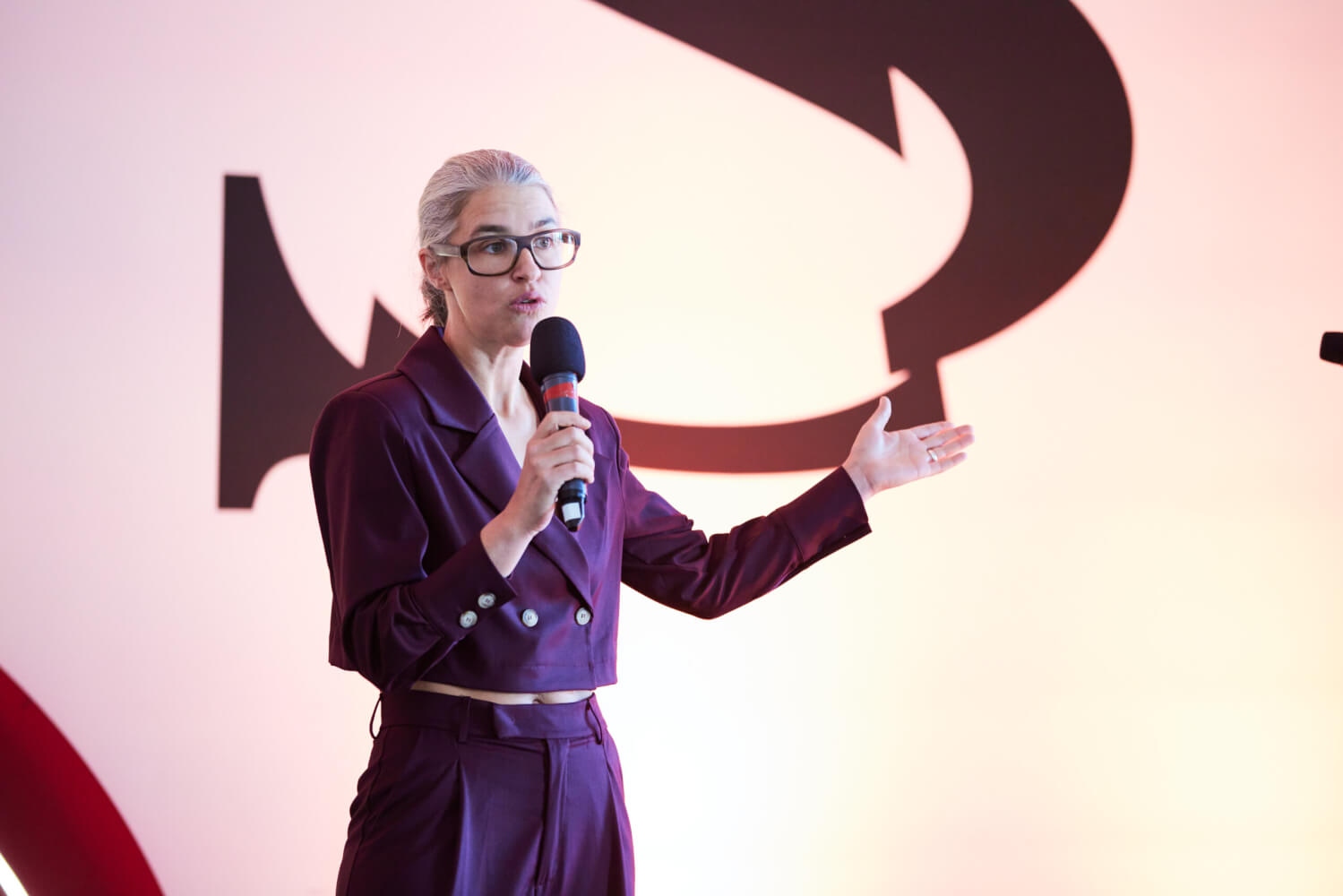 eine Person hält in der rechten Person ein Mikrofon, der linke Arm ist ausgestreckt