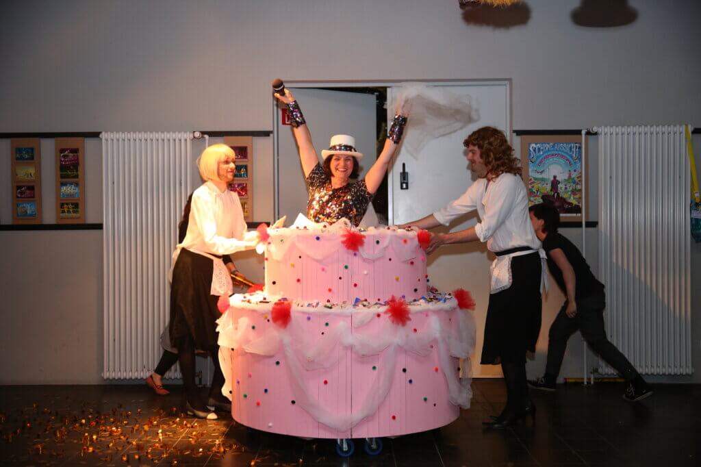 eine Person kommt aus einer Geburtstagstorte