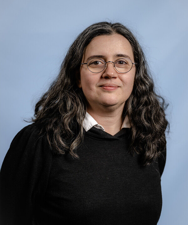 Zu sehen ist ein Portät von Michaele Dicu, Leiterin der Jungen Oper am Rhein. Sie trägt eine Brille mit einem dünnen dunklen Rand und einen schwarzen Pullover.