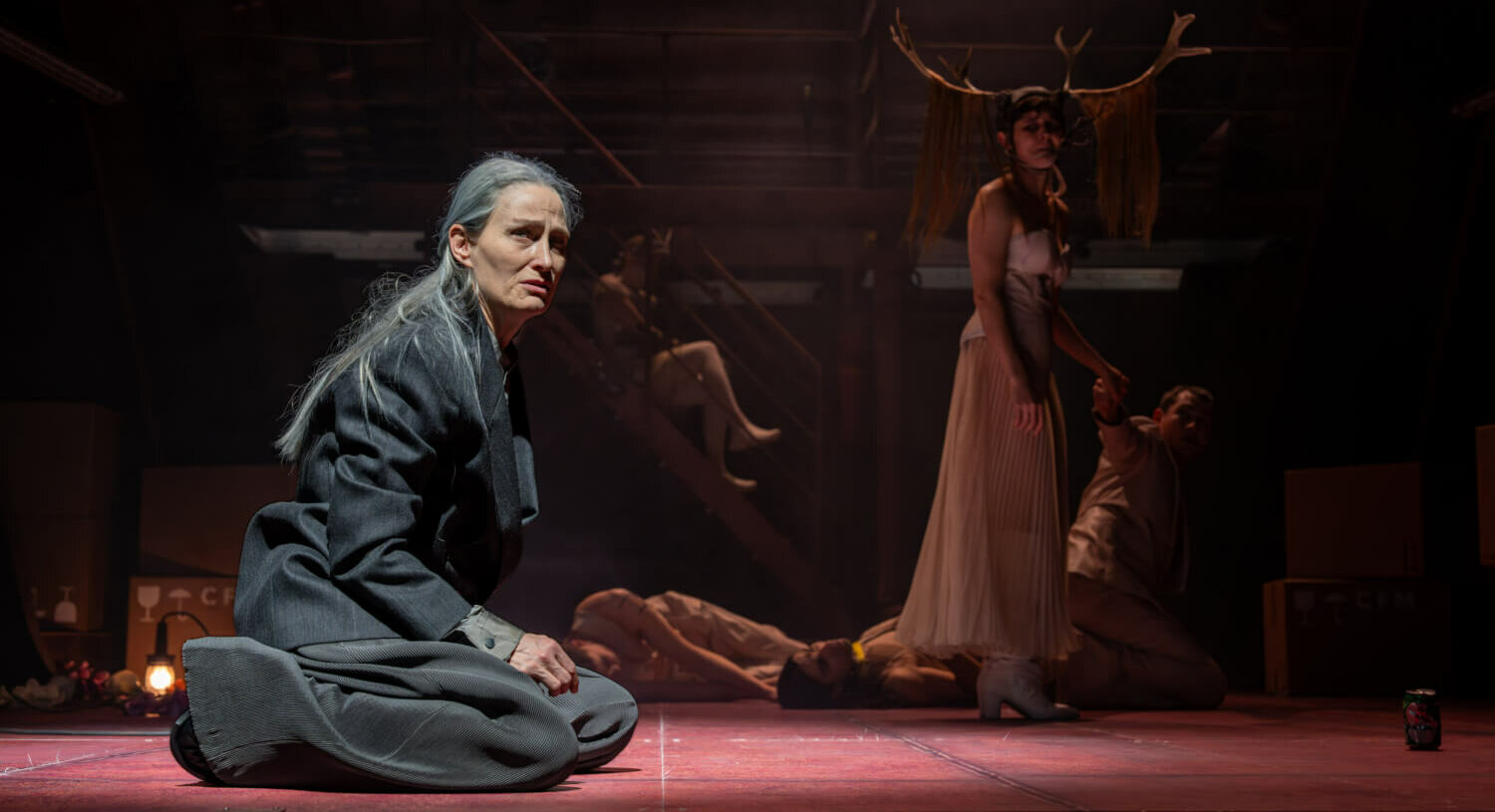 Yvon Jansen sitzt auf dem Boden. Hinter ihr stehen Darstellende mit Geweih.