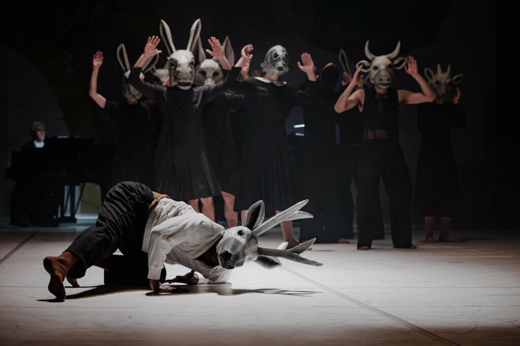 Marcos Novais mit Hirschmaske und im Hintergrund das Ensemble mit weiteren Tiermasken in „Cantos“ von Maciej Kuźmiński am Hessisches Staatstheater Wiesbaden