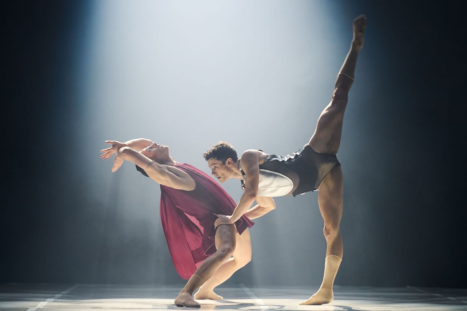 Die Neukreation „Ikarus“ an der Staatsoper Hannover mit Nikita Zdravkovic (r.) und James Nix. Ein Mann lehnt sich weit ins Hohlkreuz, die Arme über dem Kopf. Der andere Mann fasst ihn mit den Händen an den Oberschenkeln und macht einen senkrechten Spagat.