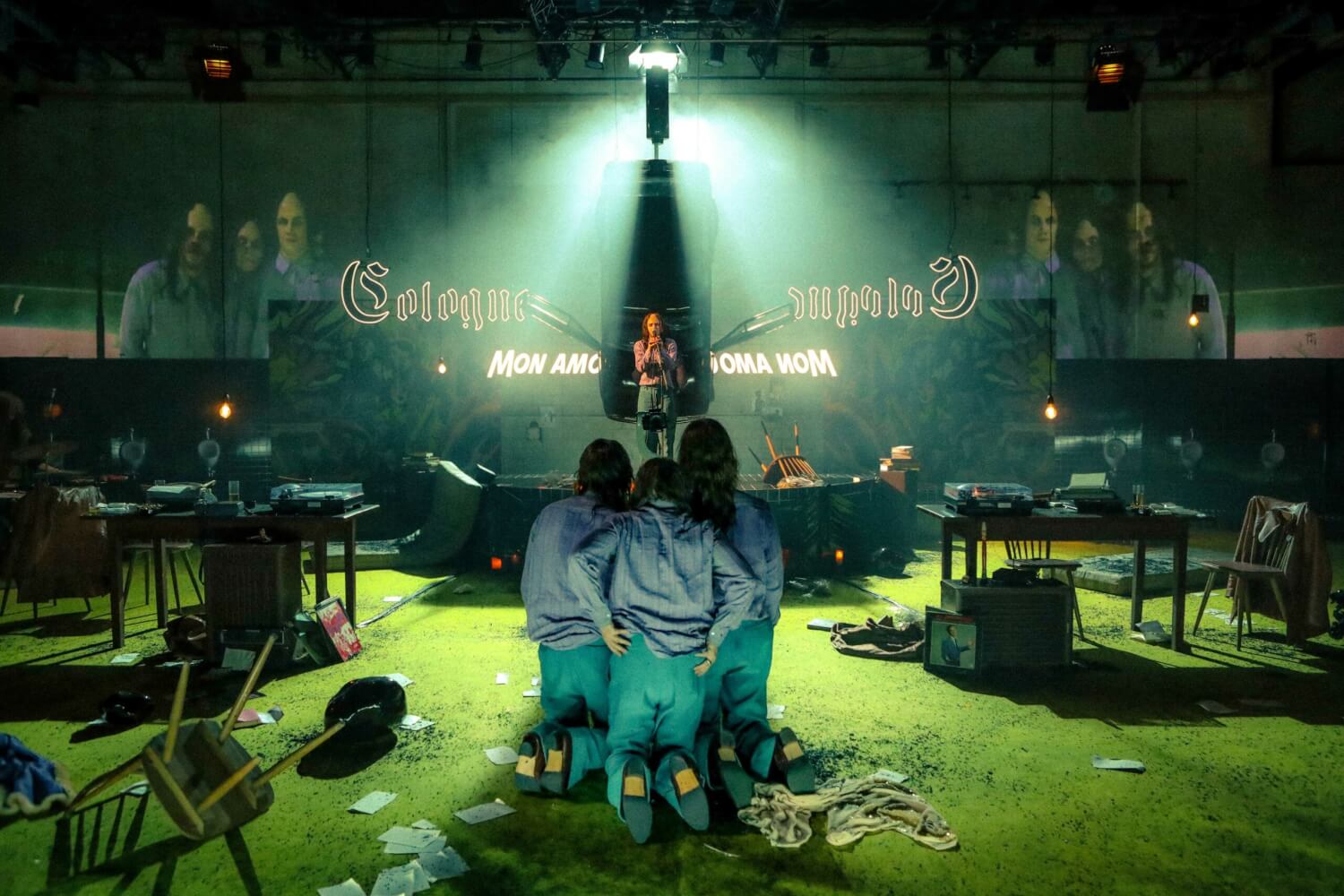 Eine Bühne, im Vordergrund knien drei Personen, eine steht im Hintergrund