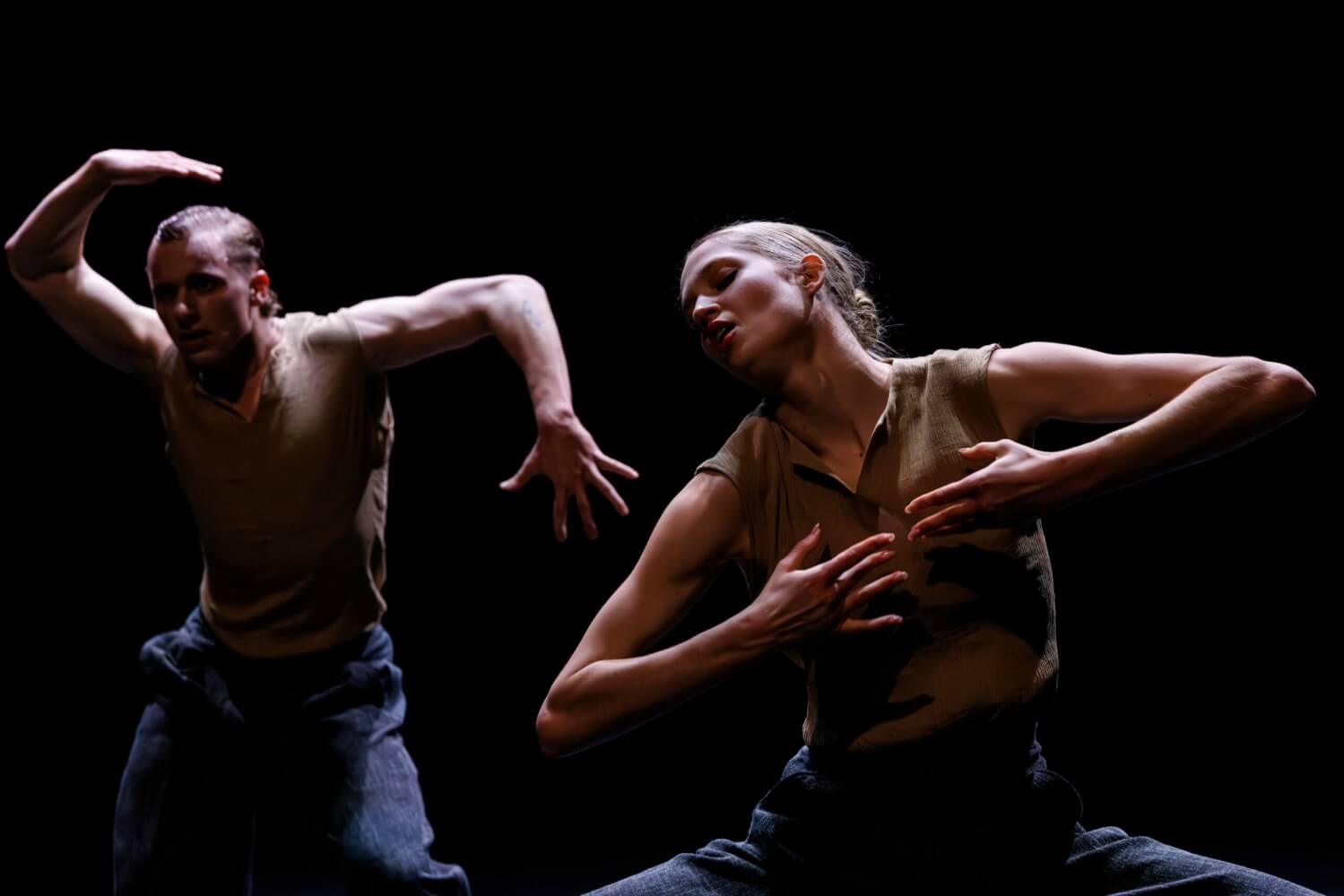 „Radical Classical“ von Gauthier Dance Juniors, Choreografie von Marco Goecke. Ein Tänzer im Hintergrund links verdreht beide Arme. Eine Tänzerin im Vordergrund hält beide Arme vor die Brust und wirft den Kopf zur Seite.