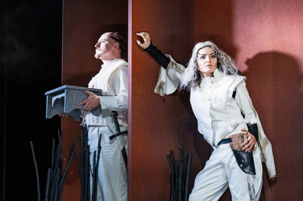 Patrick O. Beck und Zoubeida Ben Salah stehen voneinander abgewandt. Zwischen ihnen ist eine Wand an der Salah lehnt.