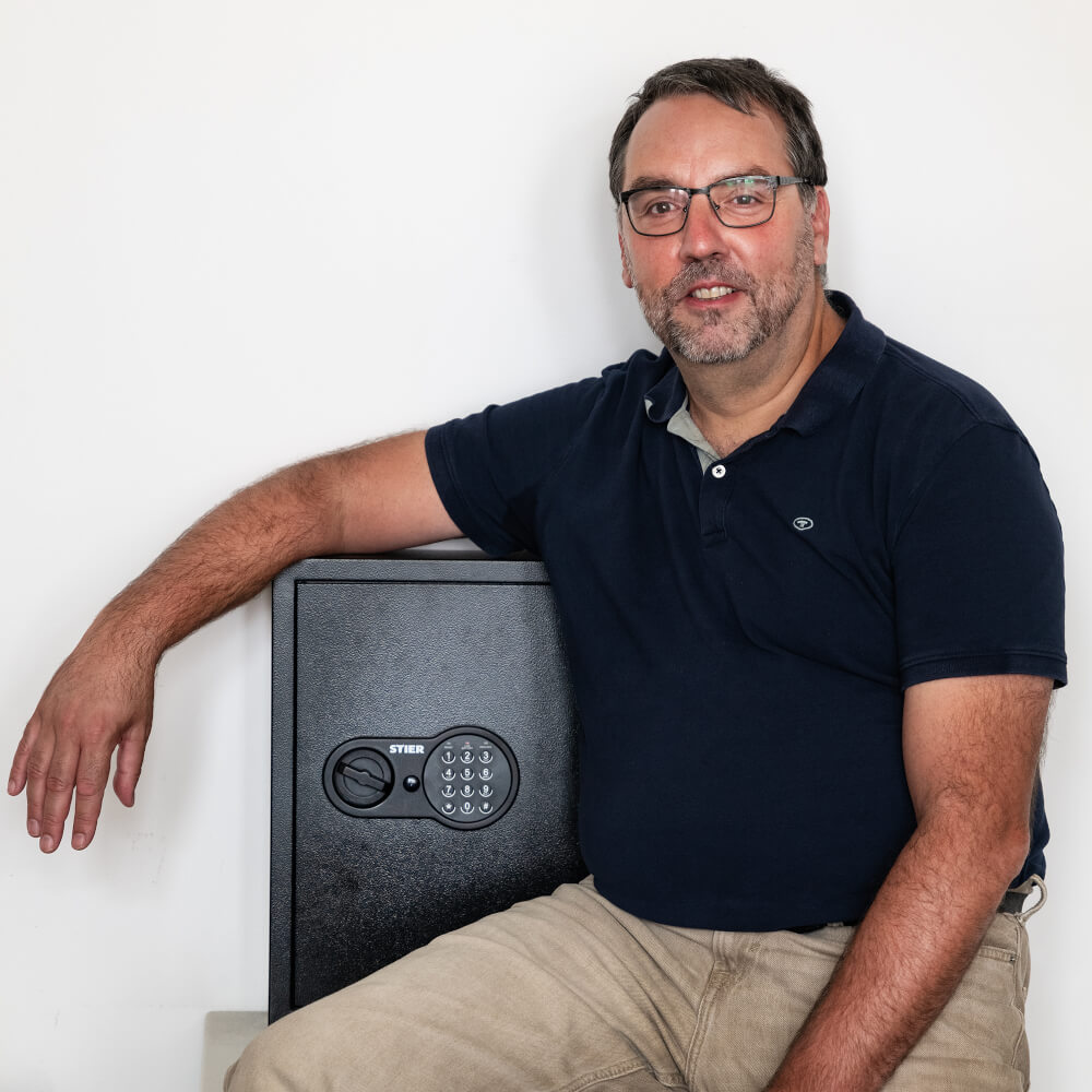 Porträt von Peter Kesten, kaufmännischer Direktor am Landestheater Schwaben, sitzend neben einem Tresor.