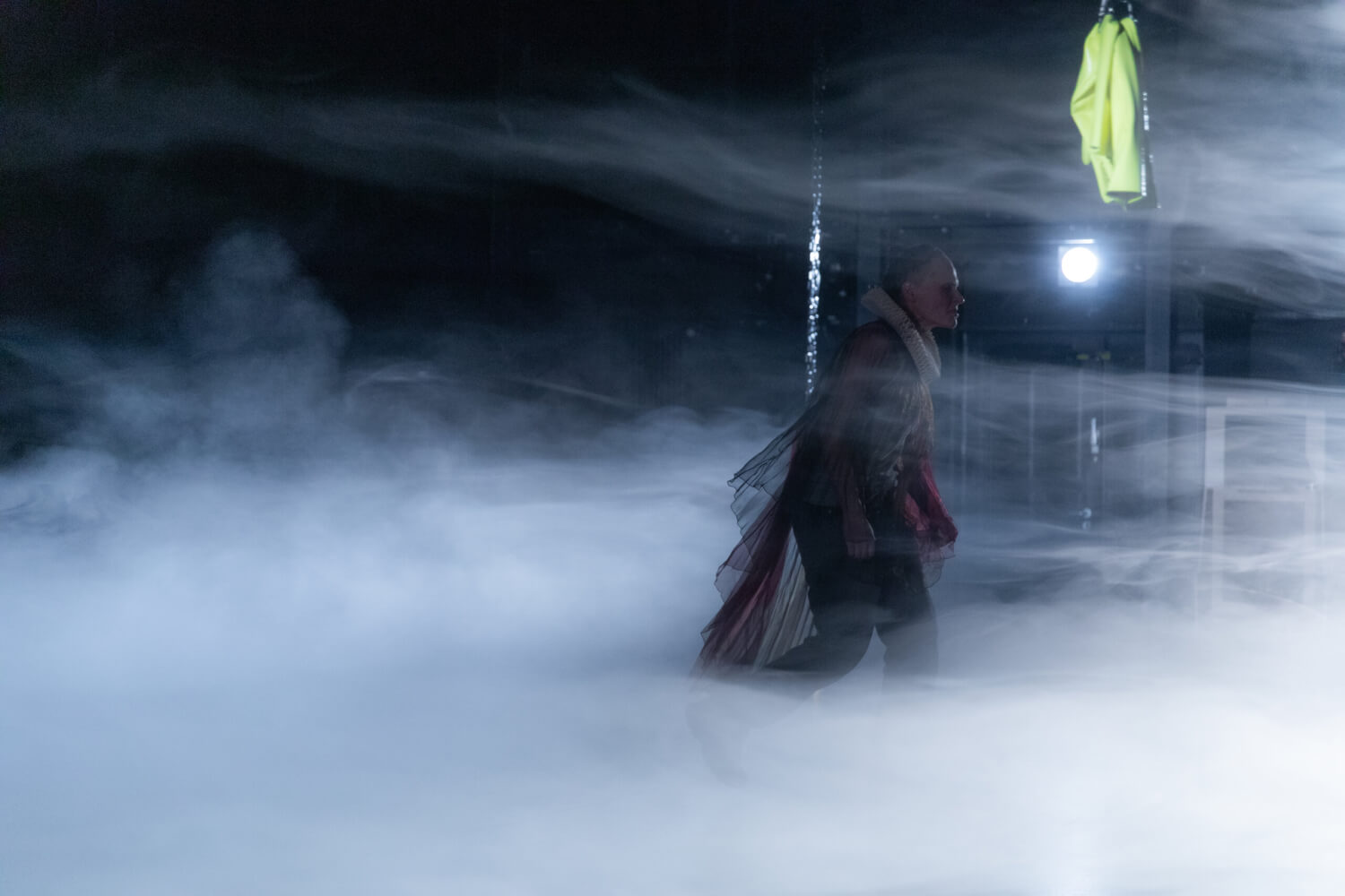 Nadine Geyersbach stapft als düstere Gestalt auf die rechte Bühnenseite durch dichten Nebel.