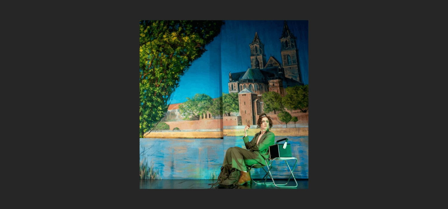 Eine Person sitzt vor einer großen Leinwand, auf die Magdeburg gemalt ist.