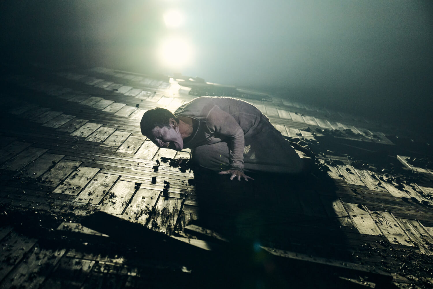 „Kassandra“ von Mathis Nitschke, Stefan Behrisch / nach Christa Wolf am Theater Bielefeld. Eine Frau liegt schreiend auf einer Parkett-Schräge, die stellenweise mit Erde bedeckt ist. Ein starkes Licht strahlt sie von hinten an.