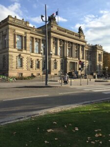 Théâtre national de Strasbourg. Das Gebäude liegt im Sonnenlicht. Davor eine Straße mit Zebrastreifen.