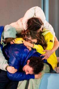 vier Darsteller:innen, die sich übereinander umarmen