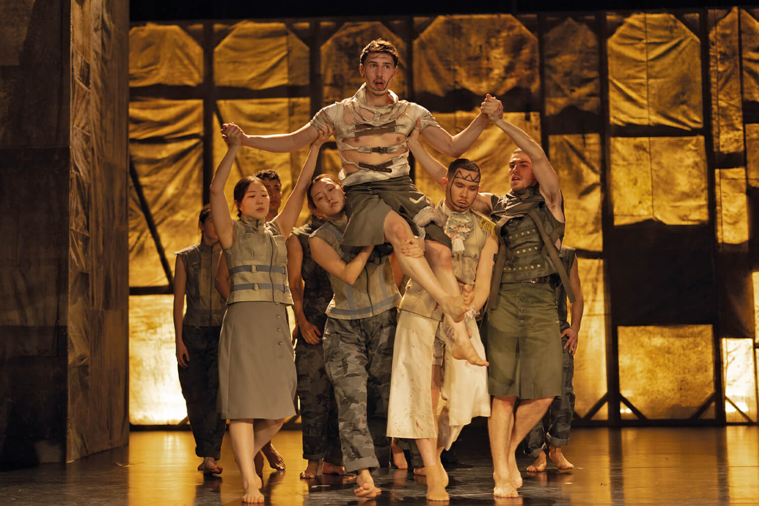 Aufführungsfoto von „Macbeth“ von der Choreografin Alessandra La Bella an den Landesbühnen Sachsen. Mehrere Person heben einen Mann hoch, tragen ihnan den Armen und Beinen.