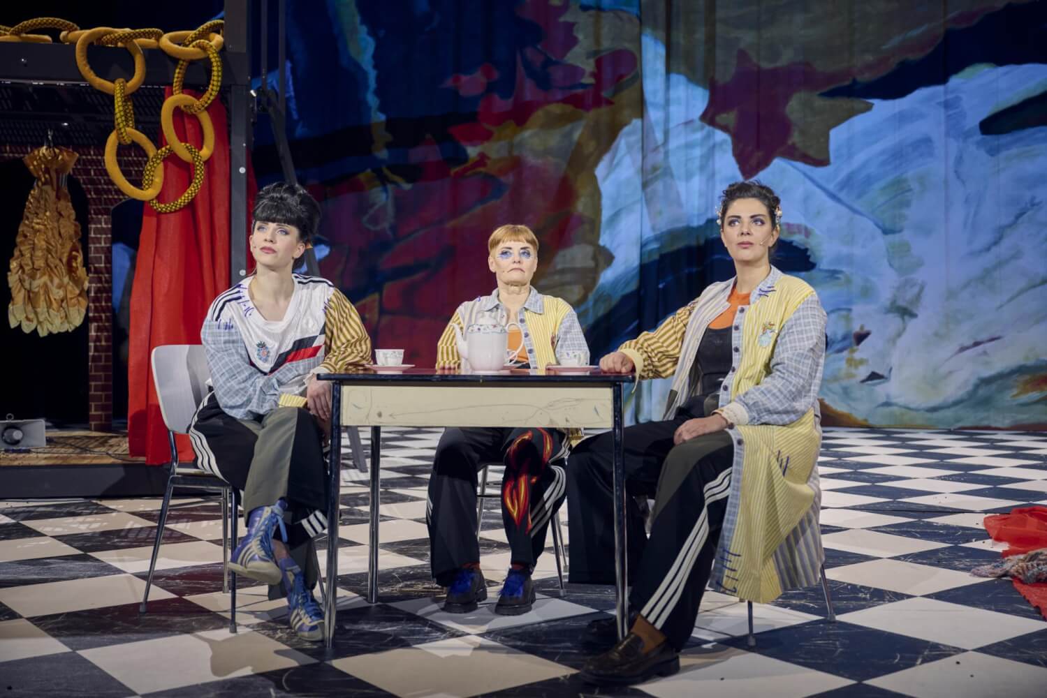 Drei Personen auf einer Bühne an einem Tisch