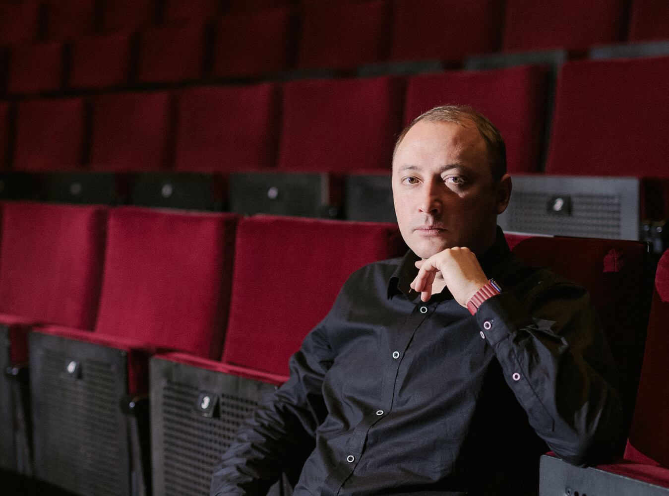 Porträt von Timofej Kuljabin, Schauspieldirektor am Staatstheater Cottbus, sitzend im Zuschauerraum.