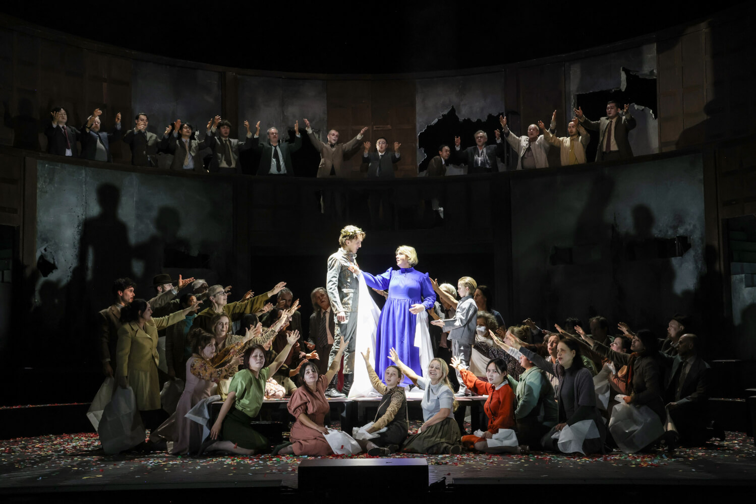 Michal Partyka und Sarah-Jane Brandon stehen in einer Menschenmenge in der Mitte der Bühne. Alle strecken ihre Hände nach ihnen aus.