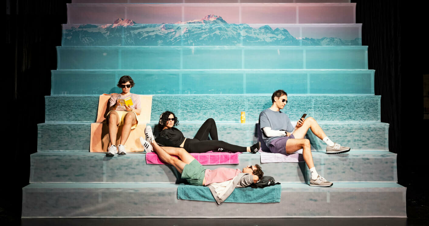 auf einer Treppe mit Berglandschaft fläzen vier Schauspieler:innen
