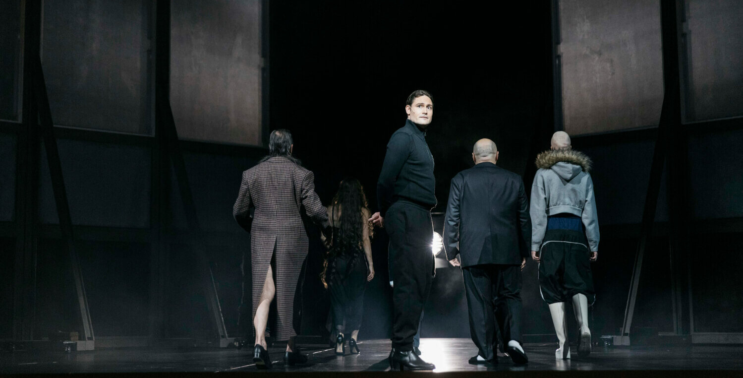 Es stehen fünf Darstellende auf der Bühne und sind am Abgehen nach hinten. Nur einer dreht sich zum Publikum und schaut zurück.