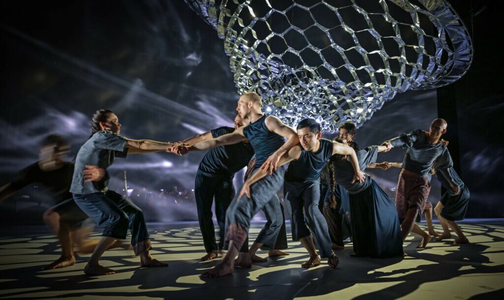 Zu sehen ist das Ensemble des Hessischen Staatsballetts zwischen Lichtreflexionen.