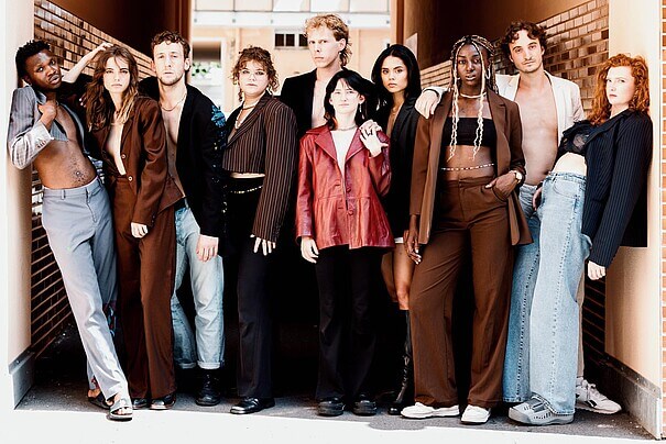 Jahrgang 2023 der Ausbildung für zeitgenössisches Theater an der Berliner Universität der Künste. Zehn Frauen und Männer stehen zwischen zwei Häuserwänden nebeneinander.