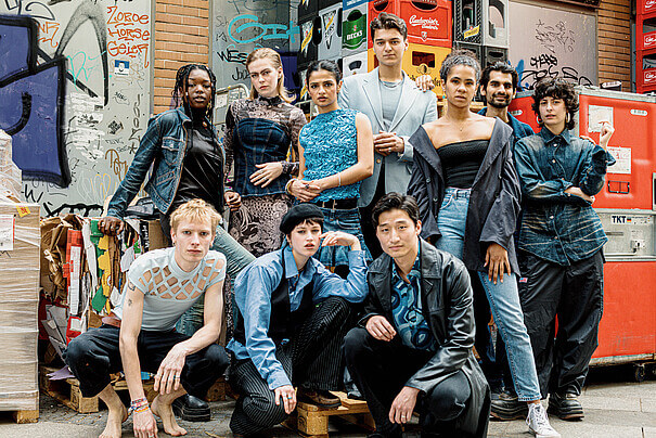 Jahrgang 2024 der Ausbildung für zeitgenössisches Theater an der Berliner Universität der Künste. Zehn Frauen und Männer in einem Hinterhof vor einer Gebäudewand und aufgestapelten Bierkästen, sechs Personen stehend, drei hockend.