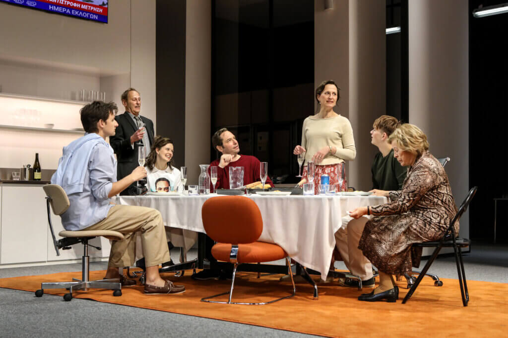 Volodymyr Melnykov, Michael Goldberg, Linda Blümchen, Florian von Manteuffel, Barbara Horvath, Dominikus Weileder und Rita Russek sitzen als Familie am Tisch. Alles scheint harmonisch und einvernehmlich.