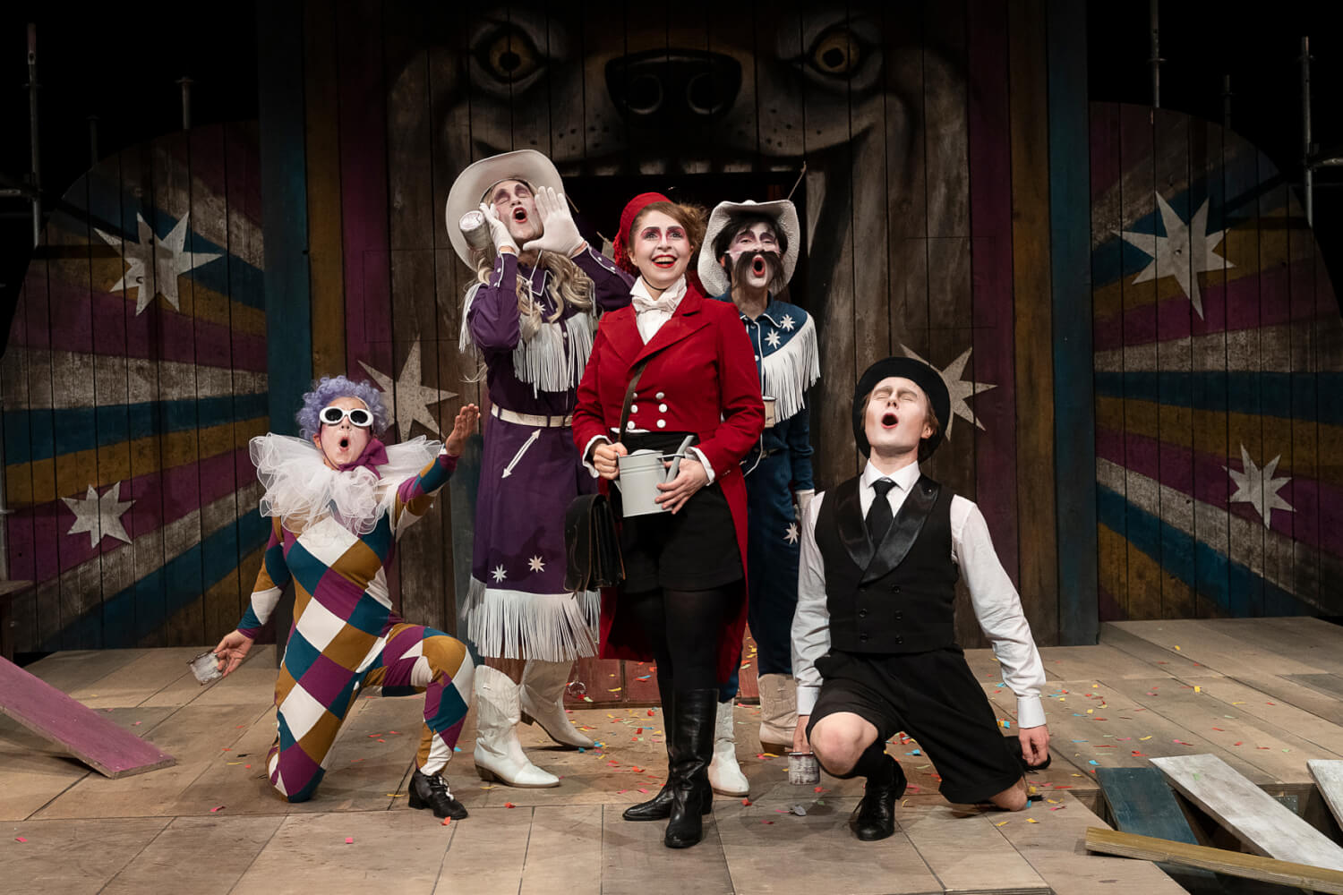 Das Ensemble macht eine Gruppenpose für das Publikum. Rotkäppchen steht in der Mitte, rechts und links knien zwei Darstellende auf dem Boden und hinter ihr stehen zwei in der Lücke. Alle sehen feierlich aus.