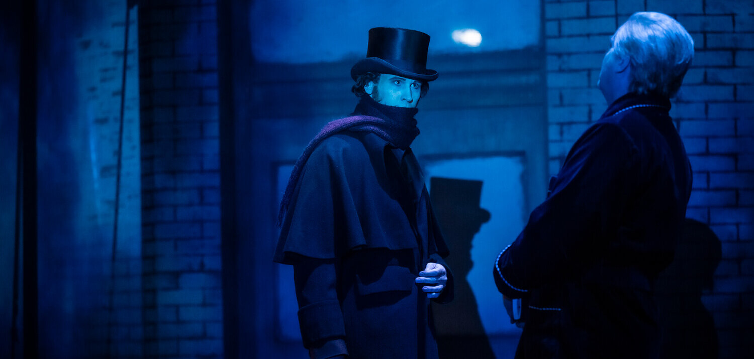 Die Bühne ist in düsteres Licht getaucht. Jack the Ripper steht dem Erzähler gegenüber.