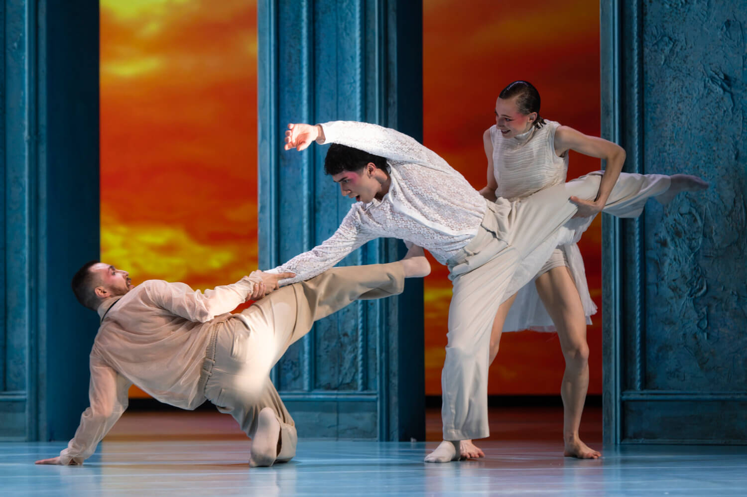 Aufführungsfoto von „Les Noces & Le Sacre du printemps“ von Didy Veldman und Ricardo Fernando am Staatstheater Augsburg. Drei Tänzer:innen die ineinander verschlungen, sich an den Beinen und Armen festhalten.