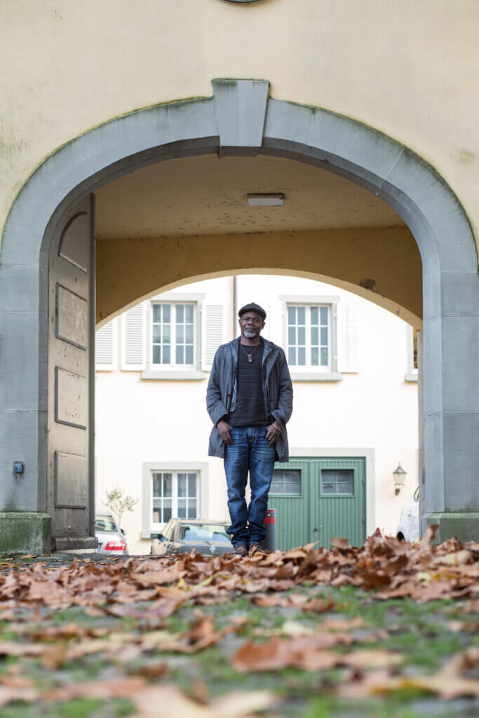 Ramsès Alfa geht durch einen Torbogen beim Münster in Konstanz. Auf dem Boden liegt trockenes Laub.