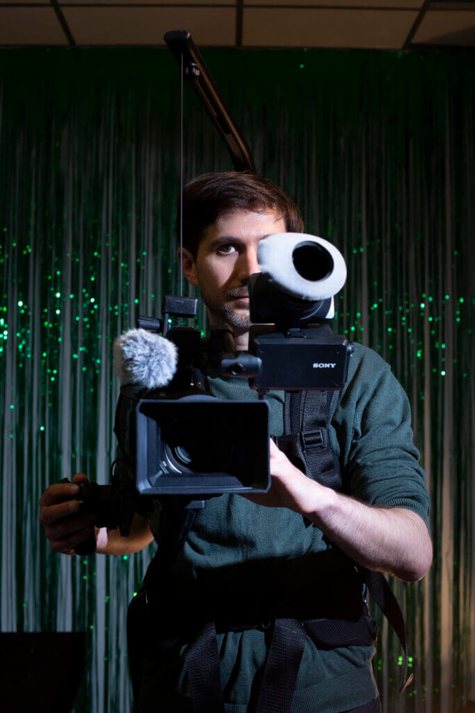 Cinematographer Lukas Raber mit seiner Kamera, die er frontal ins Bild richtet.
